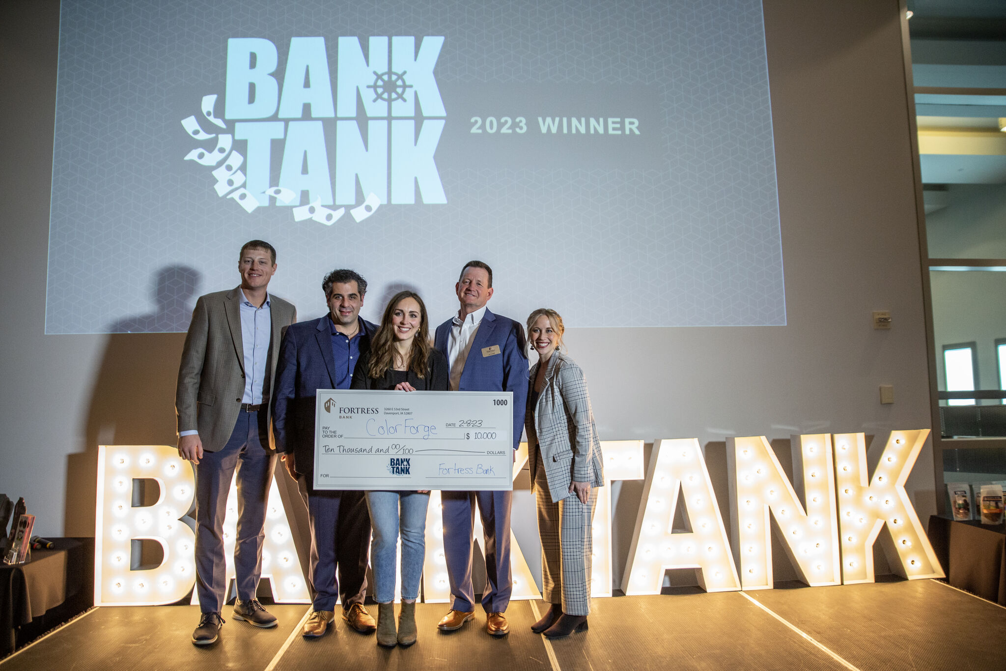 Group of people standing in front of a screen holding a big check for a grant award